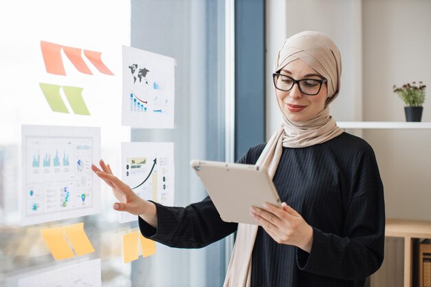 Muslim lady using tablet for checking data in graphs