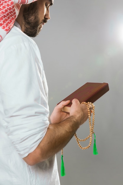 Muslim man holding quran and praying bead