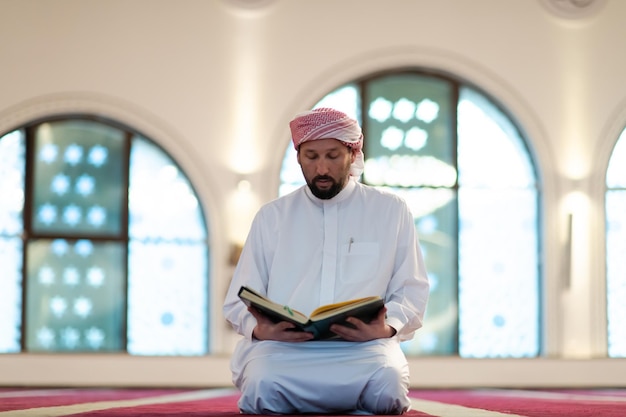 muslim man praying Allah alone inside the mosque and reading islamic holly book quran