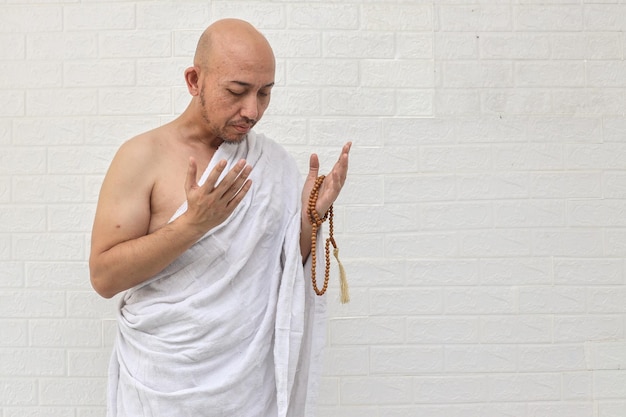 Muslim man praying wearing ihram isolated over white background