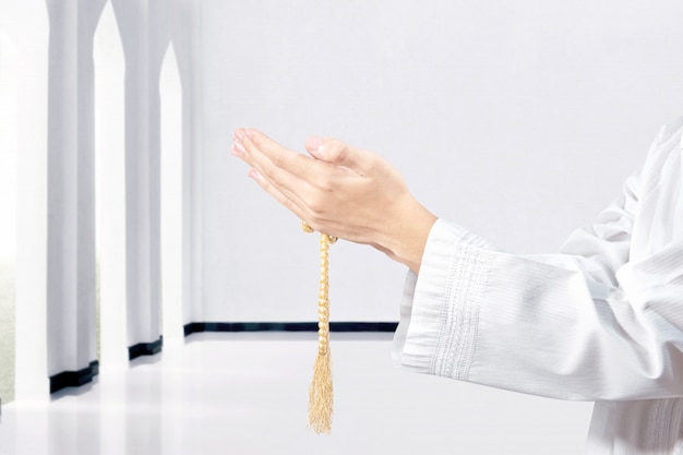 Muslim man praying with prayer beads on his hands