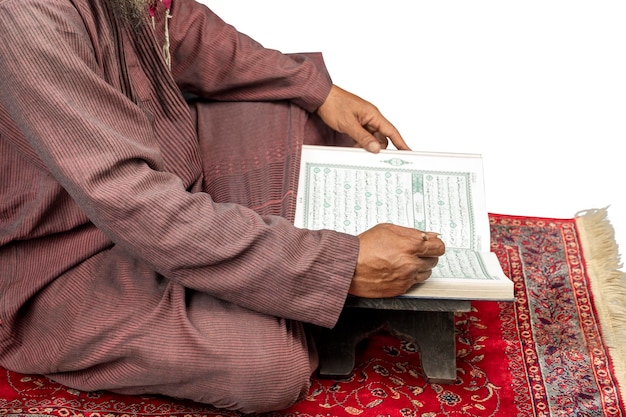 Muslim man sitting and reading the Quran on the prayer rug