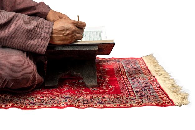 Muslim man sitting and reading the Quran on the prayer rug