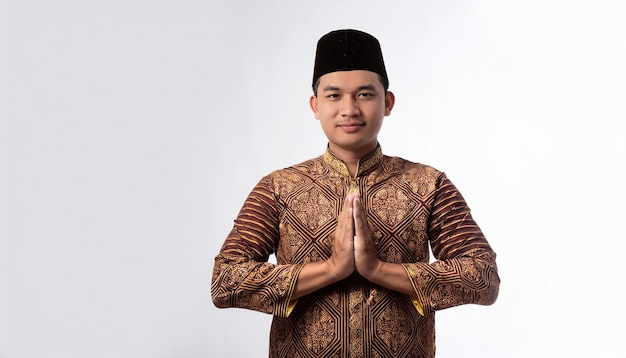 Photo muslim man in traditional clothing greeting with hands in prayer position