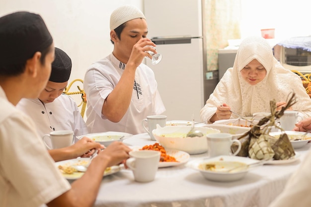 Muslim man in white koko shirt drink mineral water on glass, iftar ramadan and eid concept.