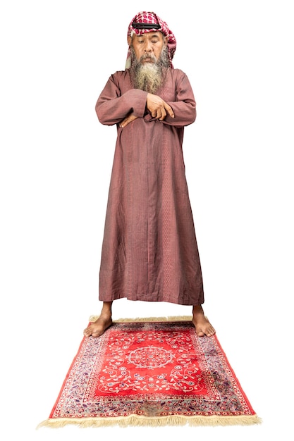 Muslim man with a beard wearing keffiyeh with agal in praying position salat on the prayer rug