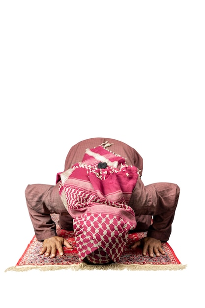 Muslim man with a beard wearing keffiyeh with agal in praying position salat on the prayer rug