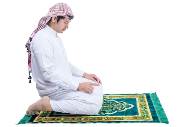 Muslim man with keffiyeh with agal in praying position salat on the prayer rug