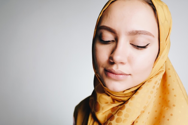 Muslim modestly dropping eyes looking down background gray