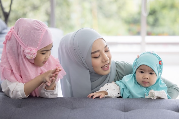 Muslim mom in hijab is her little daughter sitting in the living room, Loving Relationship