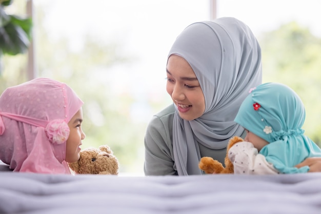 Muslim mom in hijab is her little daughter sitting in the living room, Loving Relationship