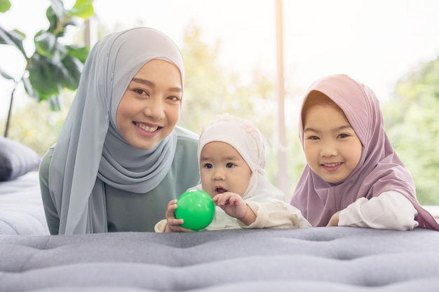 Muslim mom in hijab is her little daughter sitting in the living room