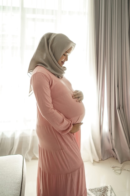 Muslim pregnant woman asian at home looking at her belly