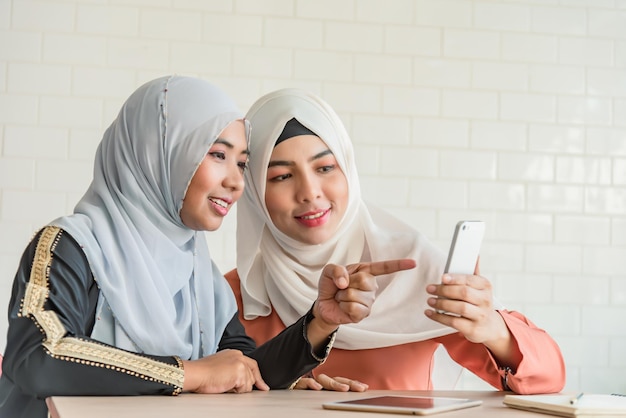 Muslim two woman use smart phone check email asian girl look at mobile look social media