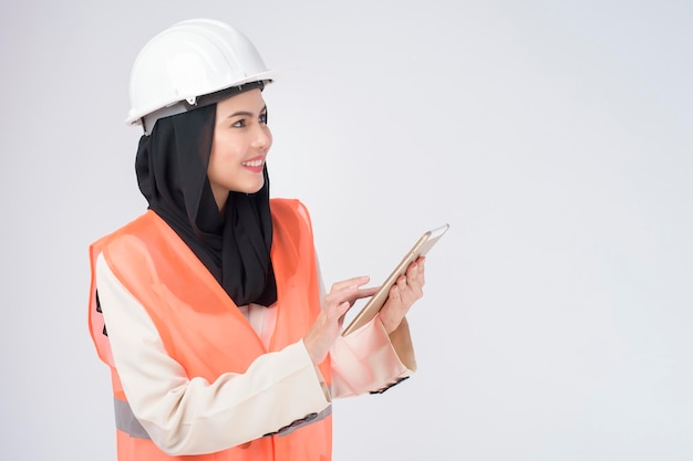 A muslim woman engineer wearinng a protective helmet over white backgroud studio