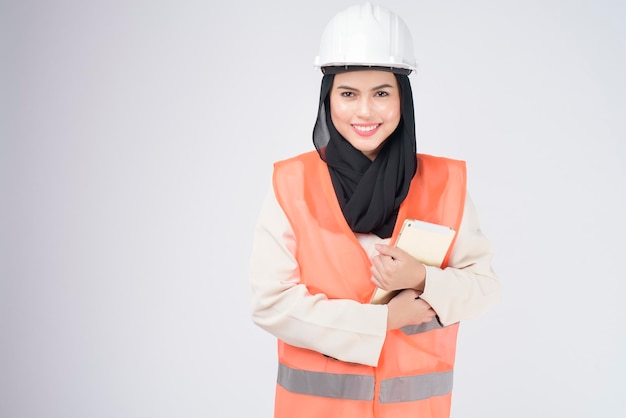 A muslim woman engineer wearinng a protective helmet over white backgroud studio