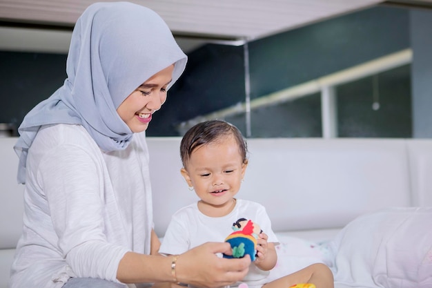 Muslim woman playing with her baby on bed