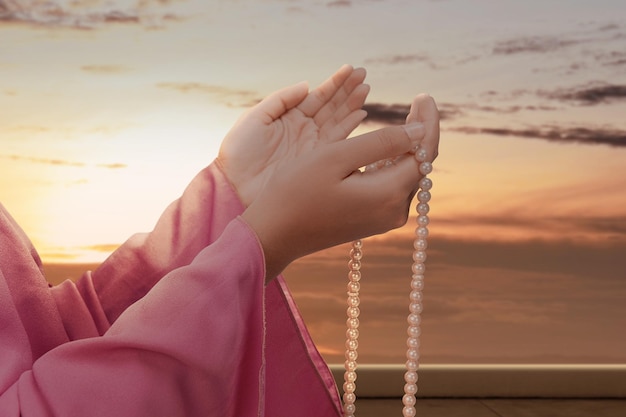 Muslim woman praying with prayer beads in her hands