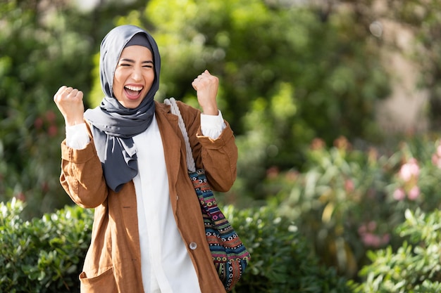 Muslim woman raising the fits to celebrate in a park