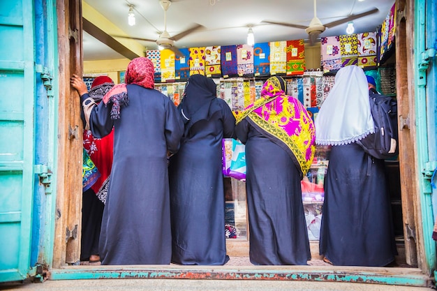 Muslim woman shopping. Muslim women traditionally dresses inside the shop choosing colorful clothes