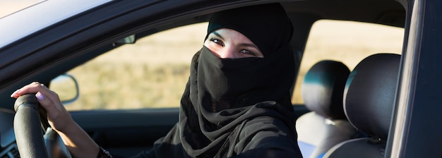 Muslim woman straightens her hijab in front of the mirror