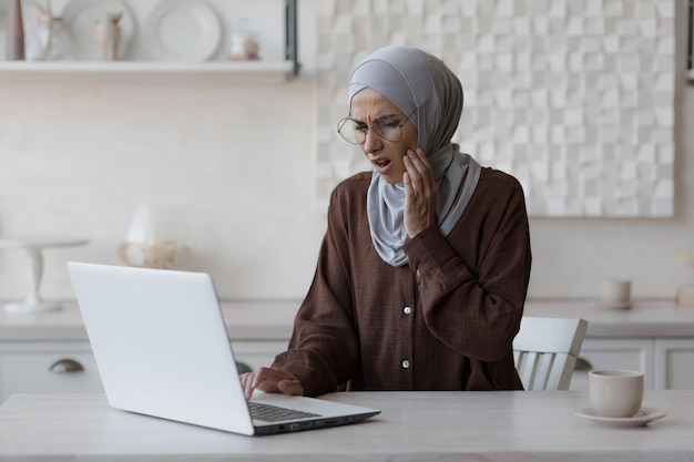 Muslim woman toothache at home business woman in hijab working remotely from home sitting in the