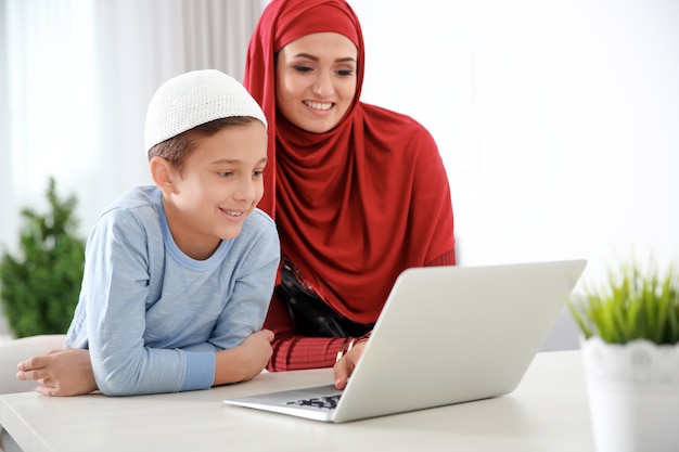 Muslim woman using laptop with her son at home