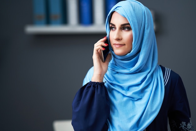 Muslim woman using smartphone in the office