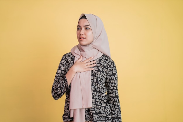 Muslim woman wearing hijab holding chest with calm expression