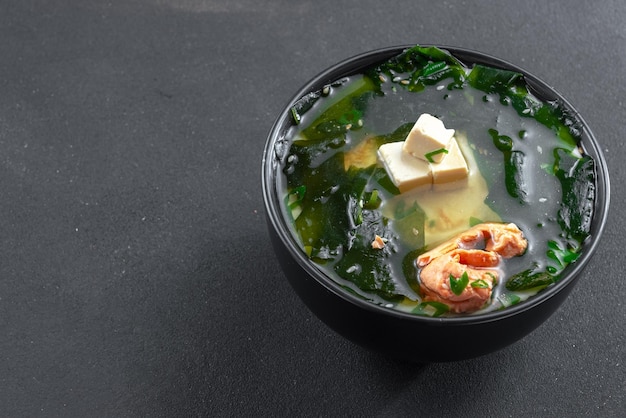 Muso soup with salmon in a black bowl on a black background asian food on a dark background