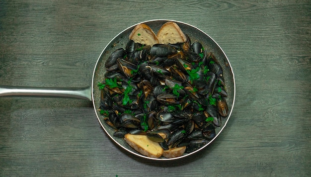 mussel soup boiled with parsley garlic in a steel pot with light background