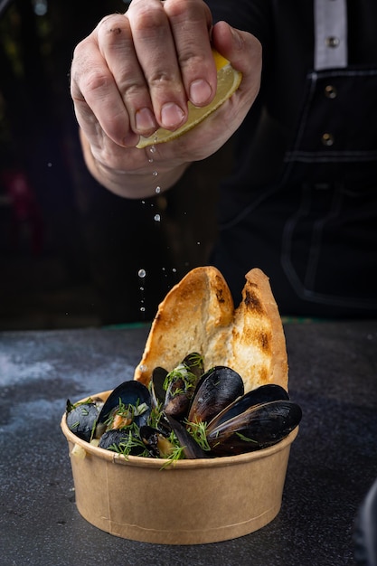 mussels in a cardboard disposable plate with lemon and parsley