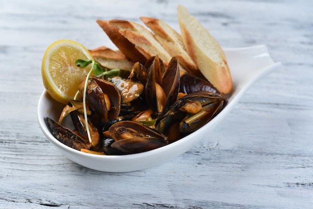 Mussels in the shell with sauce, croutons and lemon. Shellfish, grilled seafood, top view