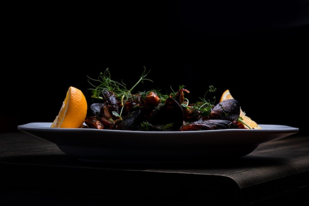 Mussels in tomato sauce with microgreens and lemon on a wooden background