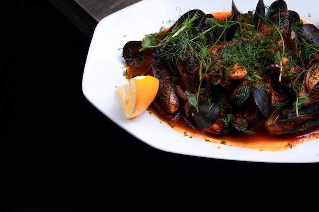 Mussels in tomato sauce with microgreens and lemon on a wooden background