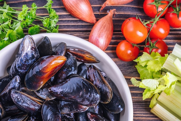 Mussels with parsley in a bowl on a wooden board. Seafood.