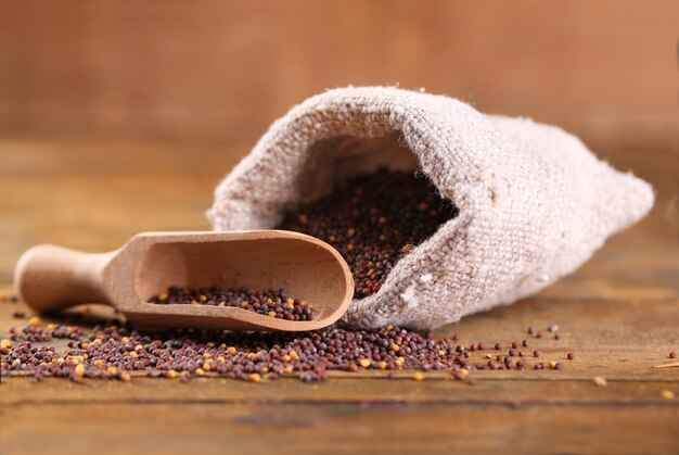 Mustard seeds in bag on wooden background