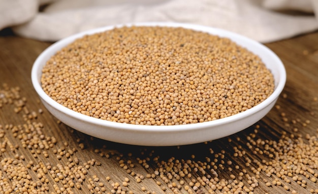 Mustard seeds in a bowl on a fabric background