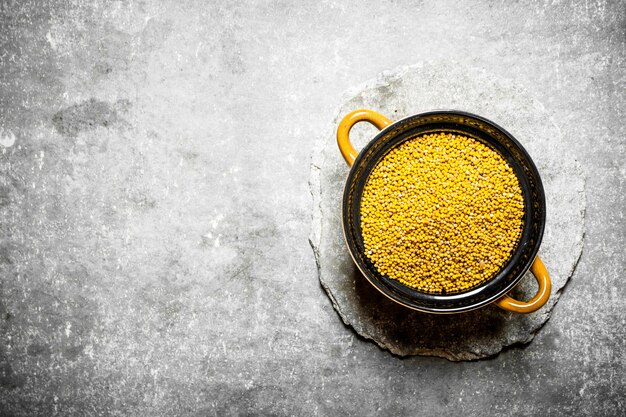 Photo mustard seeds in a bowl. on the stone table.