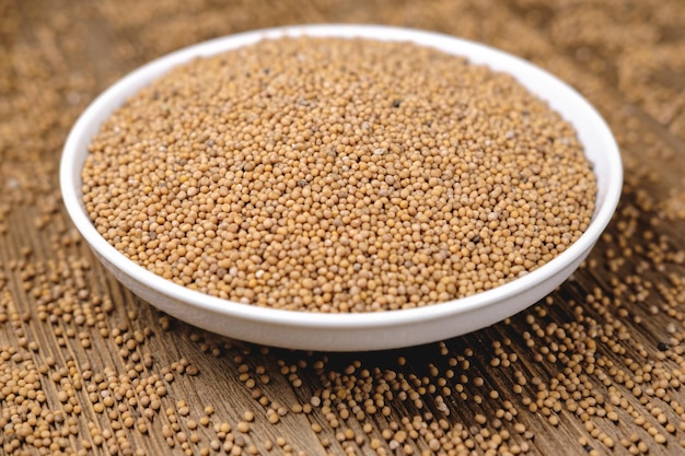 Mustard seeds in a bowl on a wooden background