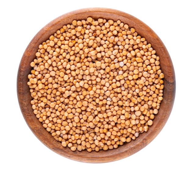 Mustard seeds in wooden bowl isolated on white background Pile of dry mustard grains Top view