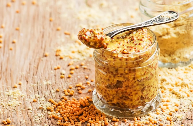 Mustard with grains ready hot sauce old wooden kitchen table background selective focus