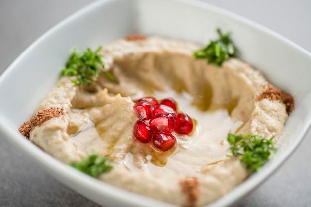 Mutabel with pomegranate seeds served in dish isolated on grey background top view of arabic food