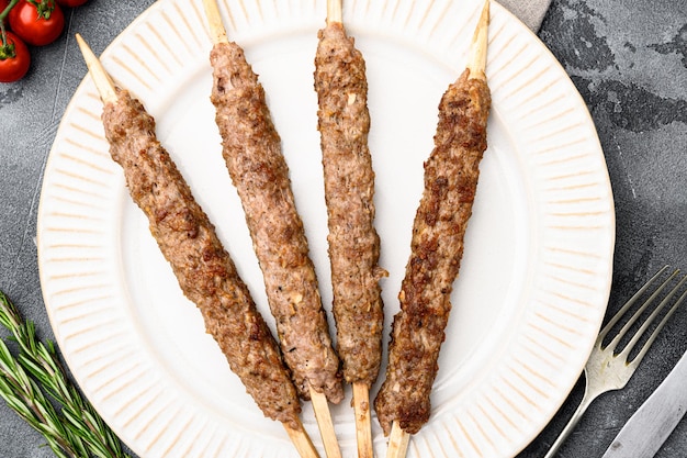 Photo mutton kebab shish skewers set, on plate, on gray stone table background, top view flat lay