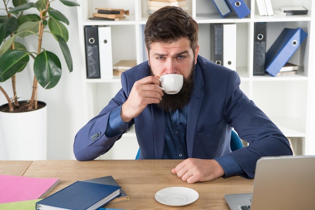 My energy. Office life routines. Respectable ceo. First coffee. Man handsome boss sit in office drinking coffee. Comfy workspace. Good morning. Bearded hipster formal suit relaxing with coffee.