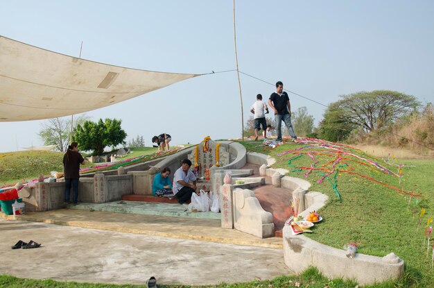 My family praying and sacrificial offering food and joss paper to ancestors in the Qingming Festival at Sritasala Cemetery on March 27 2016 in Ratchaburi Thailand