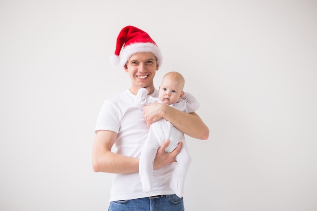 My first Christmas. Dad in santa hat holding his baby girl daughter on white background