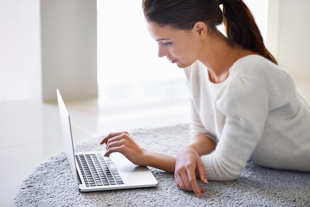 My morning dose of social networking A beautiful young woman lying on her floor at home and using a laptop