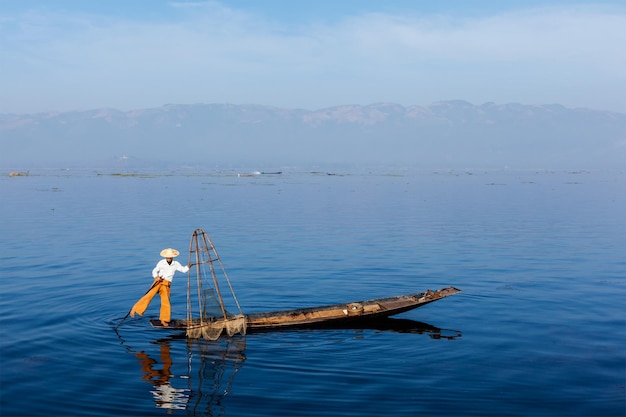 Myanmar travel attraction landmark Traditional Burmese fisherman balancing with fishing net at Inle lake Myanmar famous for their distinctive one legged rowing style