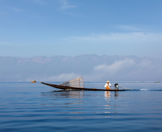 Myanmar travel attraction landmark Traditional Burmese fisherman with fishing net at Inle lake in speeding motor boat